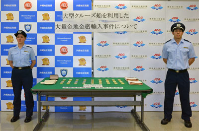 金地金を挟んで立つ税関職員 金地金を挟んで立つ税関職員